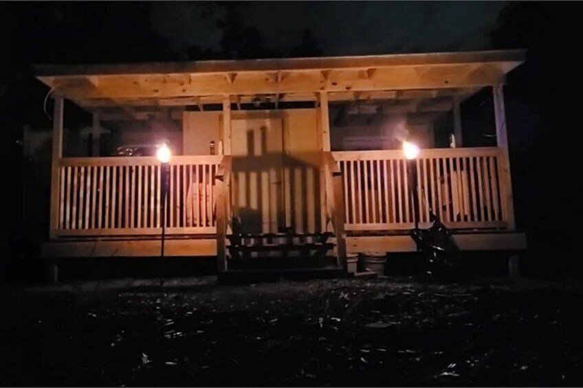 Ein hölzernes Gebäude mit Veranda, zwei Lampen und einem draußen geparkten Motorrad. 2