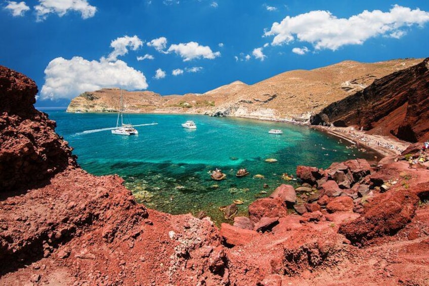 A coastal landscape with clear turquoise waters, rocky terrain, and boats anchored near the shore. 2