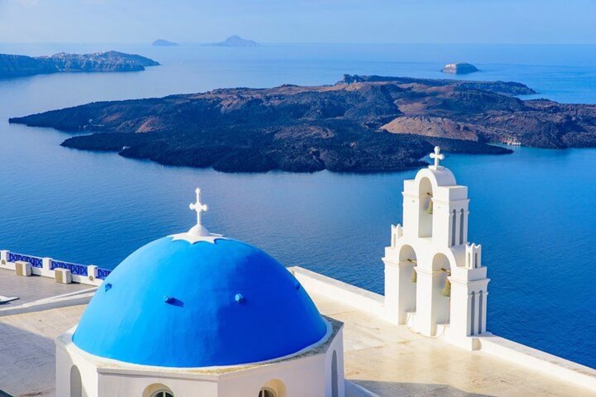A blue-domed building and a white church with a bell tower, overlooking a calm sea and rocky islands. 4