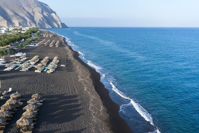 A beach with rows of sun loungers and umbrellas, a rocky coastline, and the ocean. 3