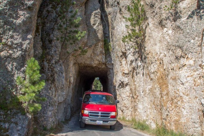 A red truck driving through a rocky tunnel. 5
