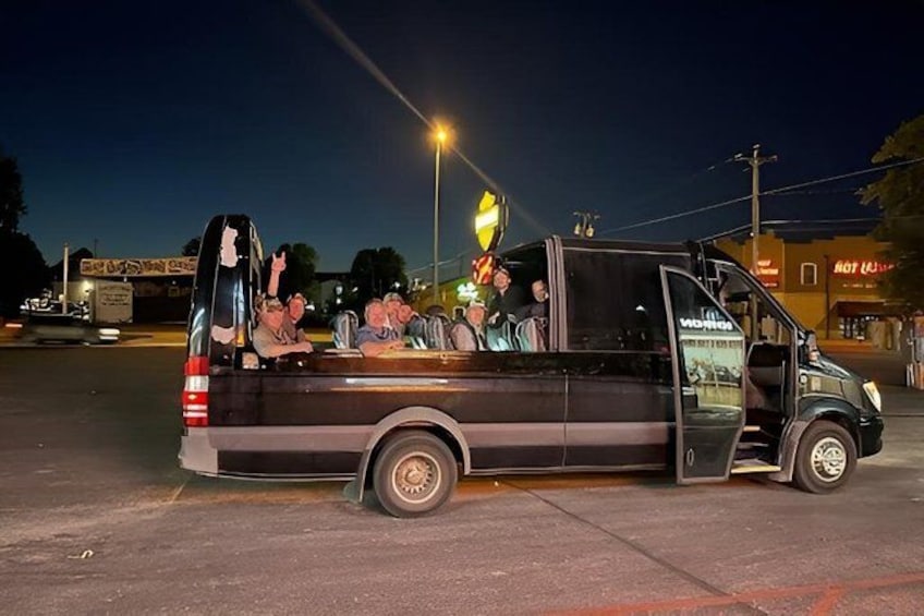 A black van with its door open, parked on a street at night. 5