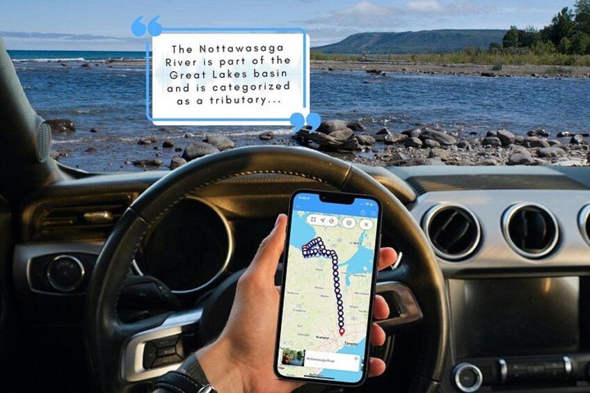 A person holding a smartphone with a map application, steering wheel, and a view of a river and rocky shoreline. 1