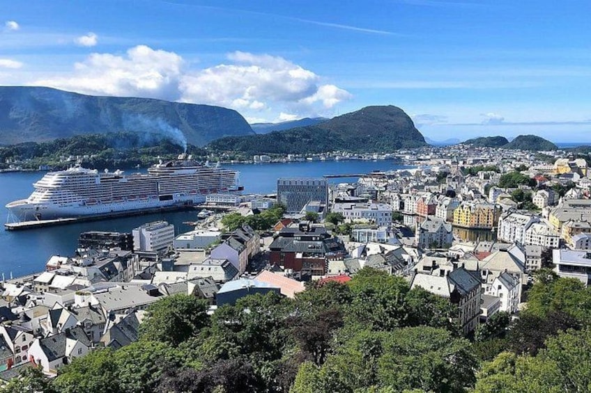 A coastal city with a large cruise ship docked, mountains in the background, and a mix of residential and commercial buildings. 1