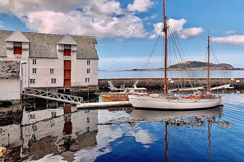 A white building with a red door, a dock, and a sailboat. 4