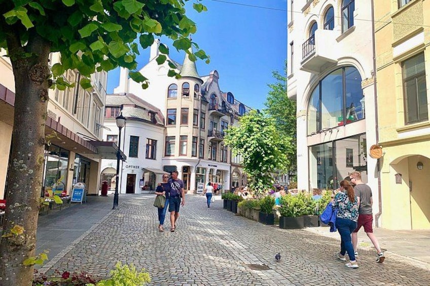 A cobblestone street with pedestrians, historic buildings, and a tree. 3