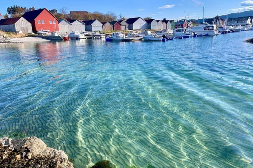 A harbor with clear water, boats, and red and white buildings. 5