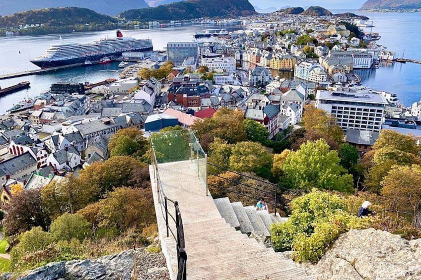 A coastal town with a large cruise ship docked, a prominent staircase leading down to the harbor, and a mix of residential and commercial buildings. 2