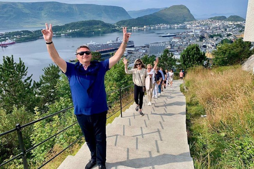A person with raised arms on a paved path with a scenic view of a body of water and hills in the background. 3