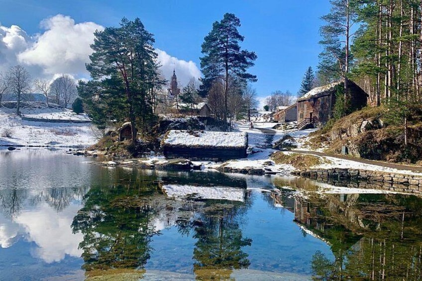 Un paisaje invernal tranquilo con un río cubierto de nieve, un puente de madera y una iglesia al fondo. 2