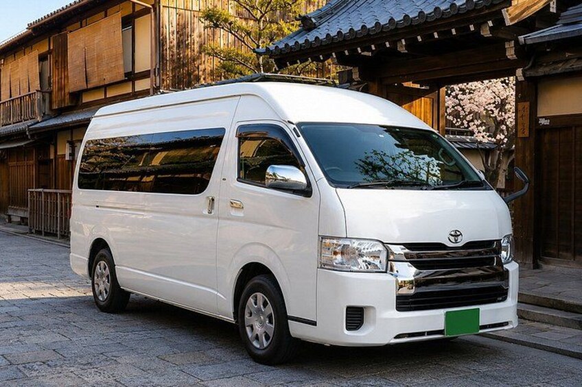 En hvid varevogn parkeret foran en traditionel japansk bygning med et flisegulvt tag. 2
