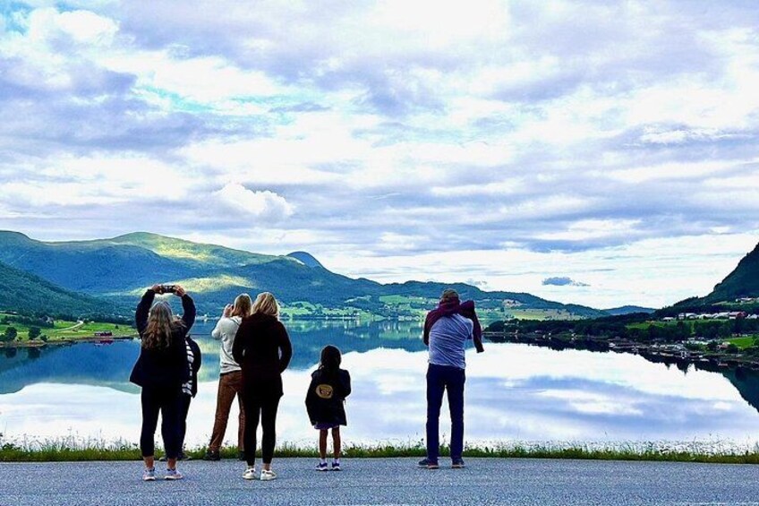 Een groep mensen staat bij een meer, met bergen op de achtergrond. 5