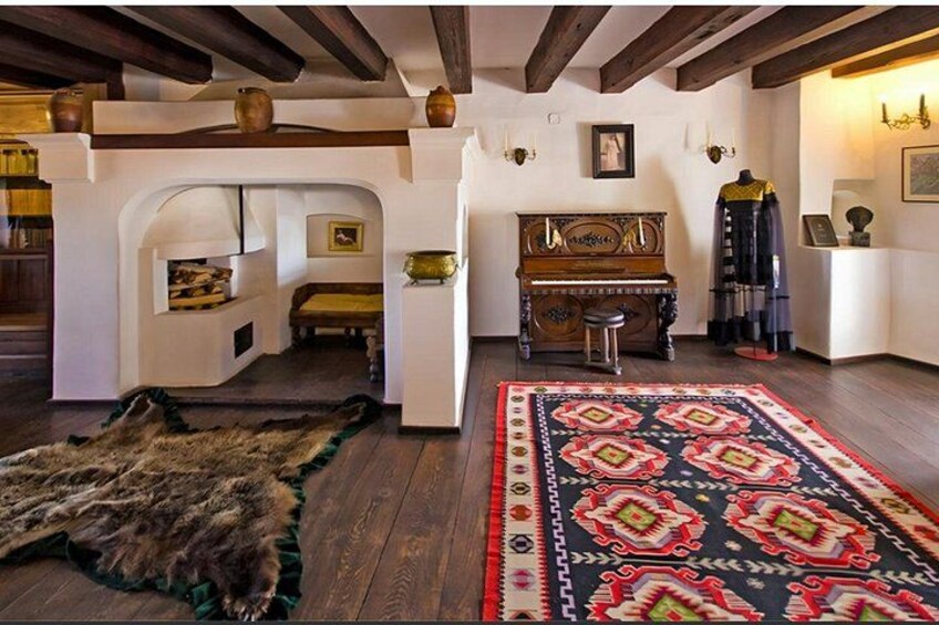 Una habitación con un piano, un manto de piel y una alfombra estampada. 4