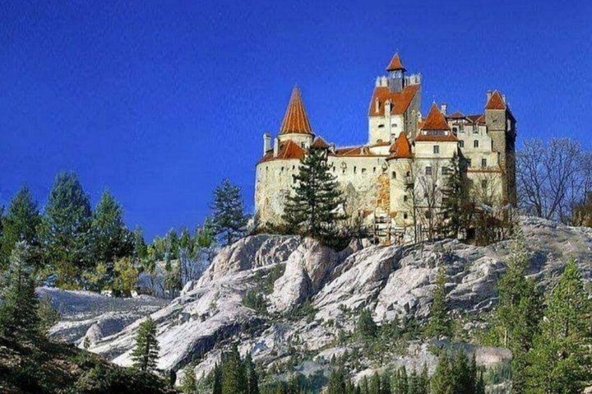 Un castillo sobre una colina rocosa bajo un cielo azul despejado. 1