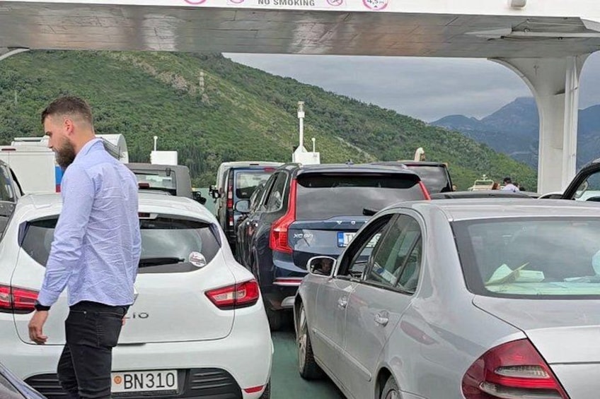 A man walking past a line of cars on a bridge with a mountainous landscape in the background. 3