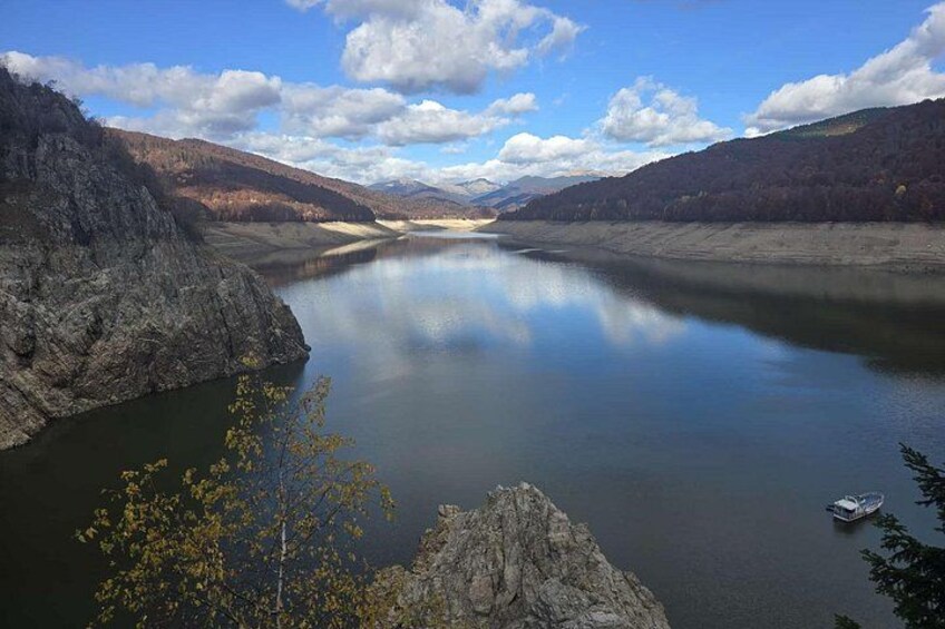 A calm river surrounded by rocky cliffs, a small boat on the water, and a clear sky. 3
