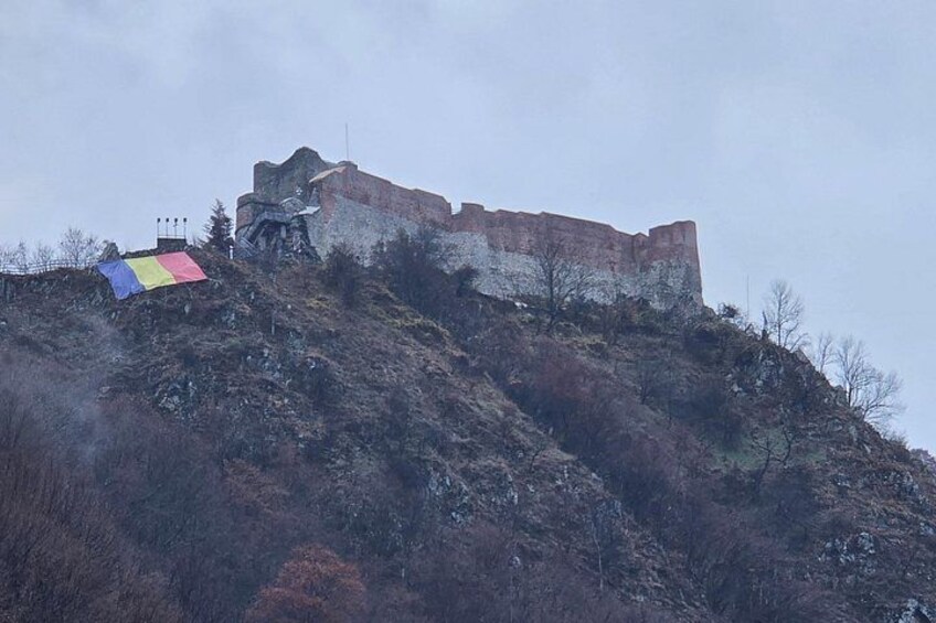 A historic stone castle on a hill with a colorful flag. 5