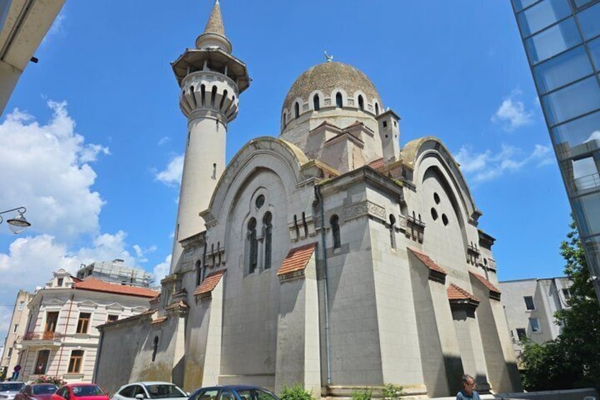 En historisk kirke med et markant minaret og kuppel, omgivet af bybygninger. 4
