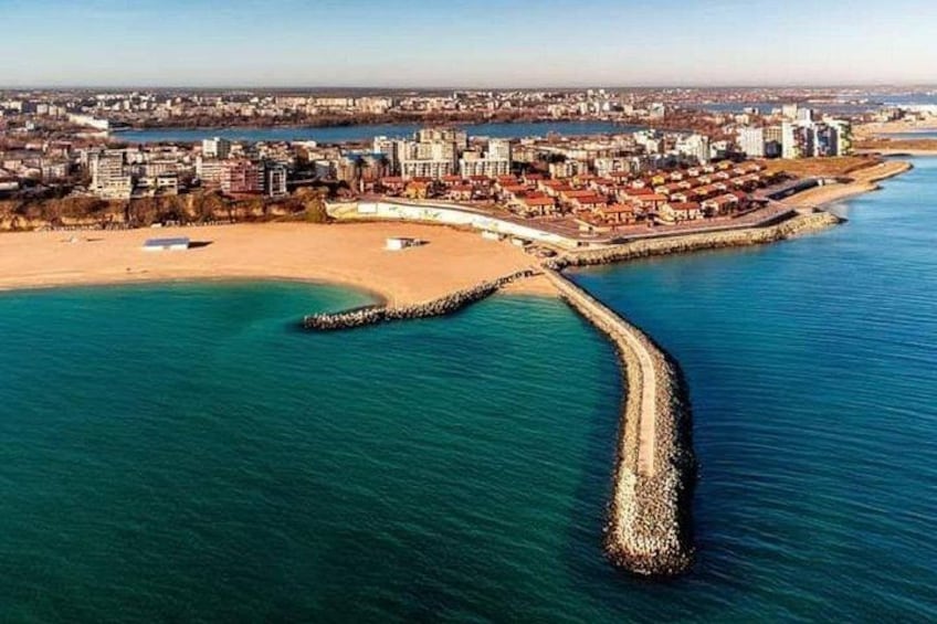 A coastal city with a beach, a breakwater, and a dense urban area in the background. 4