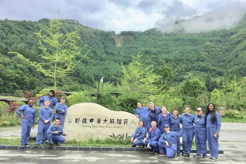 A group of people in blue uniforms posing in front of a sign with Chinese characters. 3