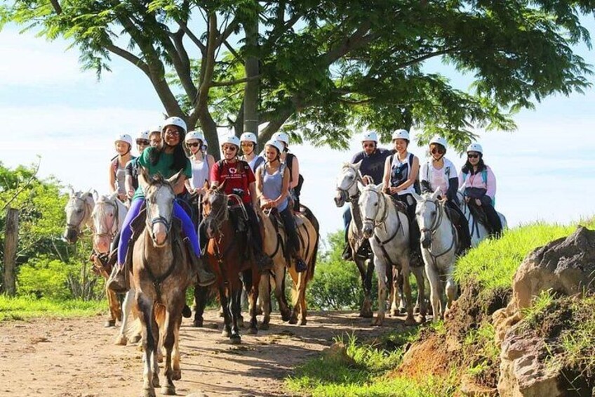 Un grupo de personas cabalgando por un sendero de tierra rodeado de vegetación. 4