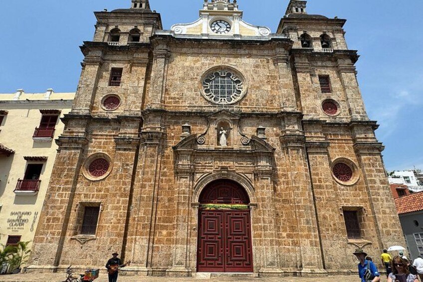 A historic church with a large clock, arched windows, and a prominent red door. 5