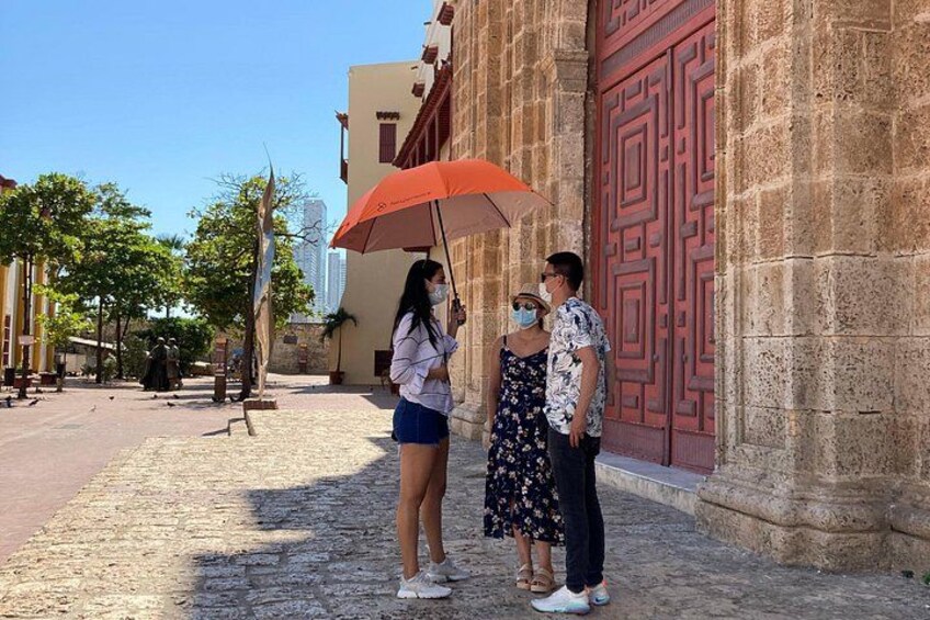 A cobblestone street with a large red door, a woman holding an umbrella, and a man in a patterned shirt. 3