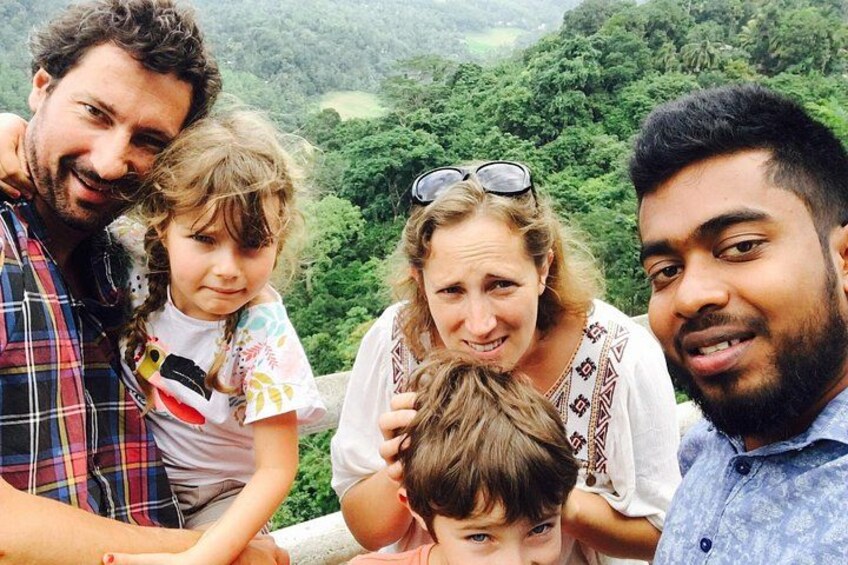 A family of four outdoors with a lush green landscape in the background. 3