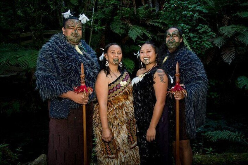 Four people in traditional attire standing in a forest. 5