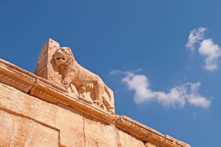 A stone lion sculpture on a building's edge under a clear sky. 5