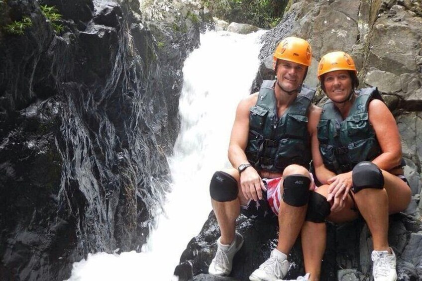 Due persone sedute su una roccia vicino a una cascata. 2