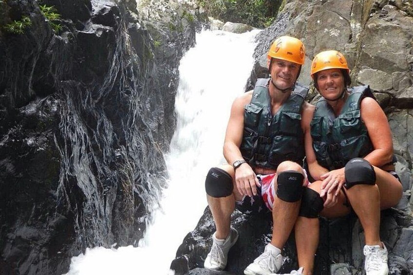 Zwei Personen sitzen auf einem Felsen an einem Wasserfall. 2