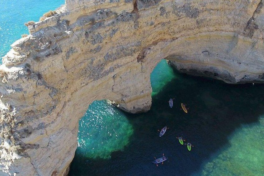 A rocky coastline with a natural arch formation and clear blue waters. 2
