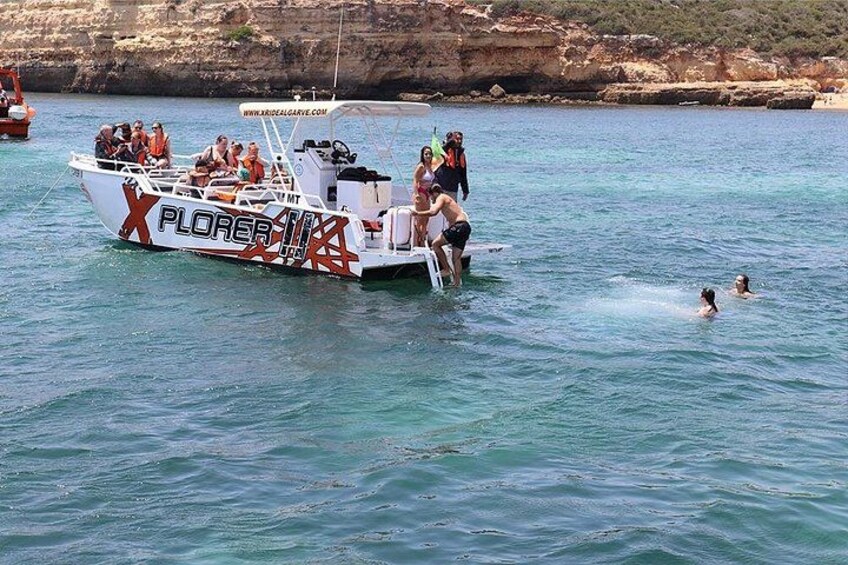 A boat named 'PLORER' with people on board and swimmers in the water. 4