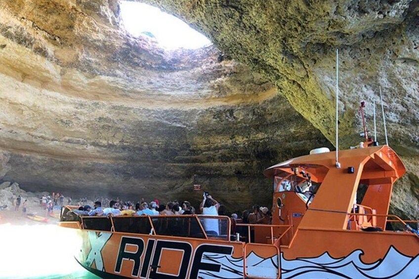 A boat named 'RIDE' with people on board, docked at a cave entrance. 3