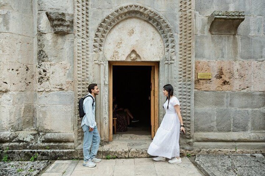 A man and a woman standing in front of an old stone building with a wooden door. 5
