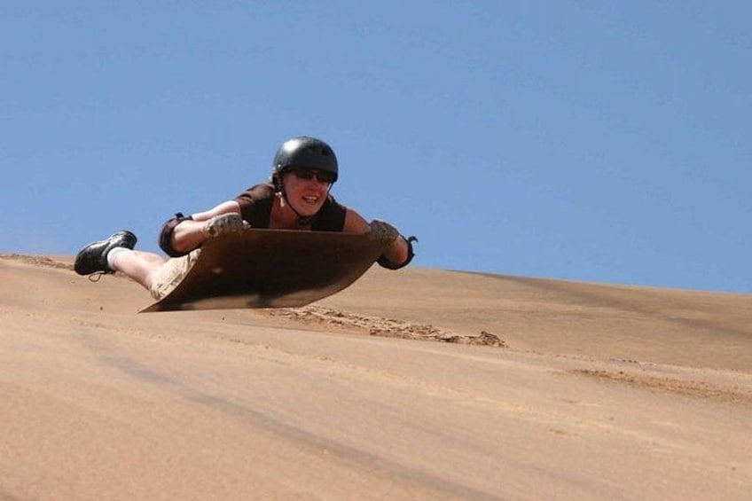 A person sledding down a sandy slope. 1