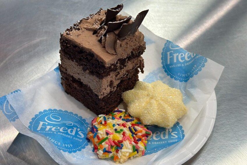 A slice of chocolate cake with frosting and sprinkles on a white plate. 5