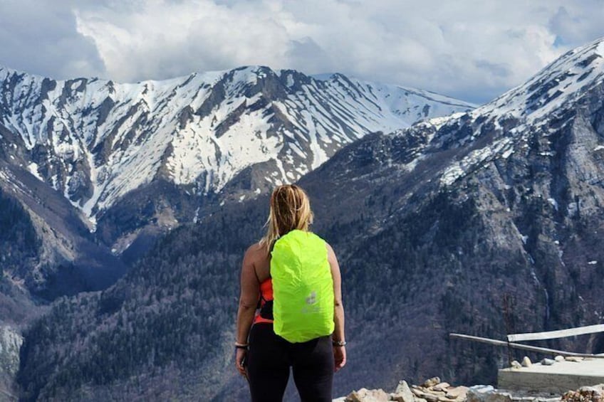Una persona de pie con una mochila verde brillante, contemplando montañas nevadas. 1