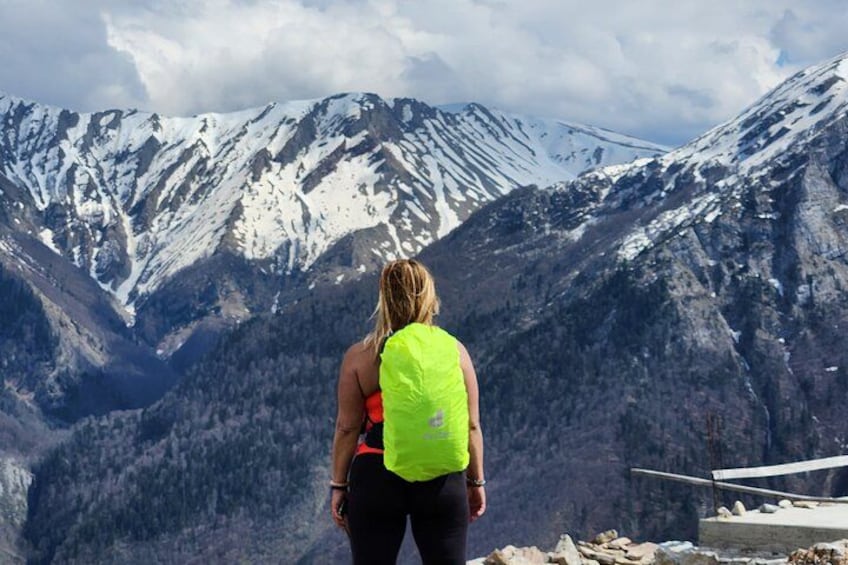 Una persona de pie en la cresta de una montaña, con picos nevados al fondo. 1