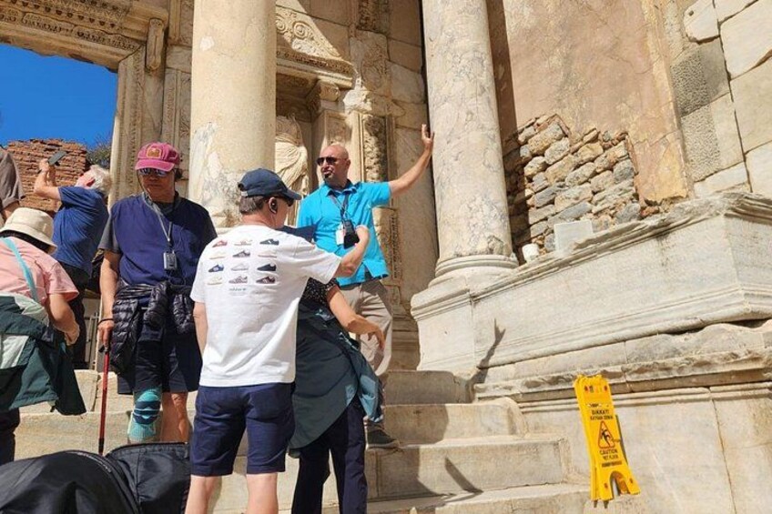 A group of people standing near ancient columns, some taking photos. 4