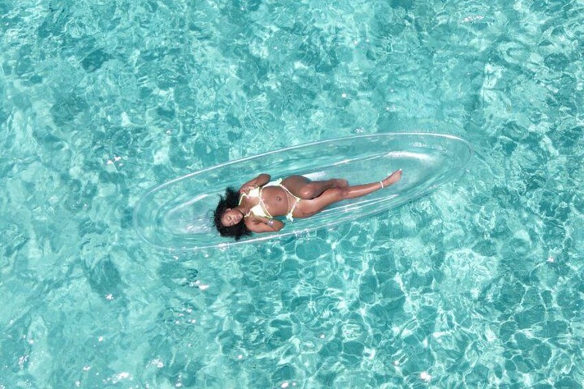 Una persona flotando en un círculo inflable sobre aguas azules y cristalinas. 4