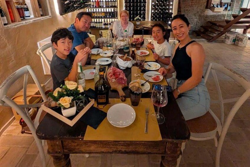 A group of people dining at a table with wine bottles, glasses, and a variety of dishes. 2