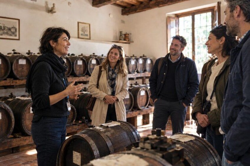 Un grupo de personas en una bodega con barriles de madera. 1
