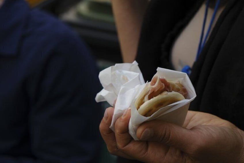 Una persona sosteniendo un sándwich envuelto. 3