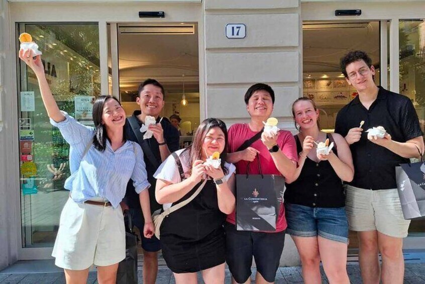 Un grupo de personas frente a un edificio, sosteniendo helados. 5