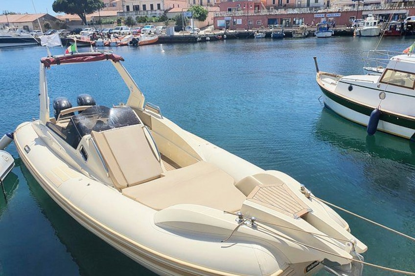 A small motorboat docked at a marina with other boats in the background. 2