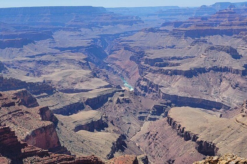 A vast canyon landscape with layered rock formations and a visible river. 5