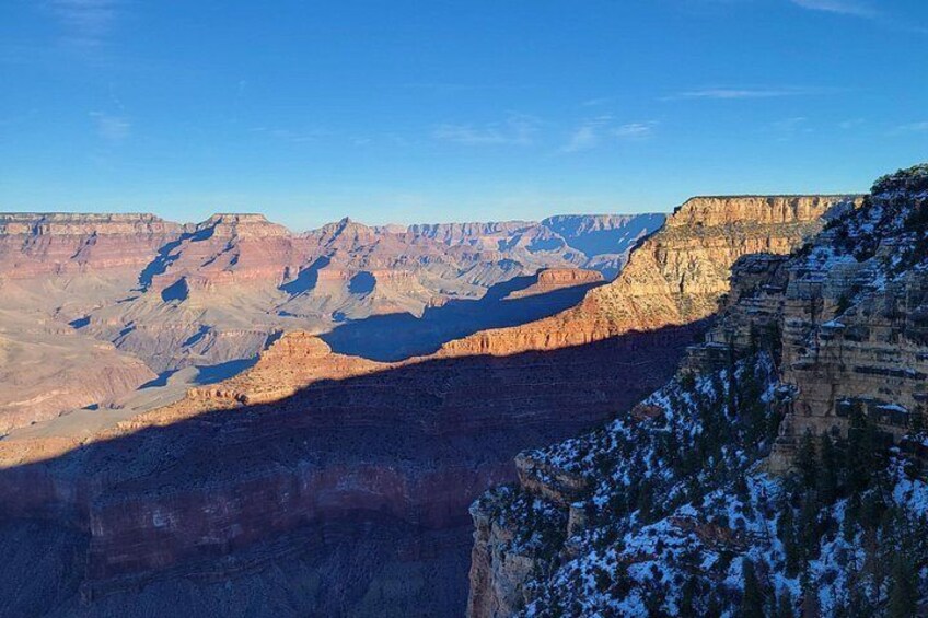 A canyon with layered rock formations and a snow-covered cliff. 4