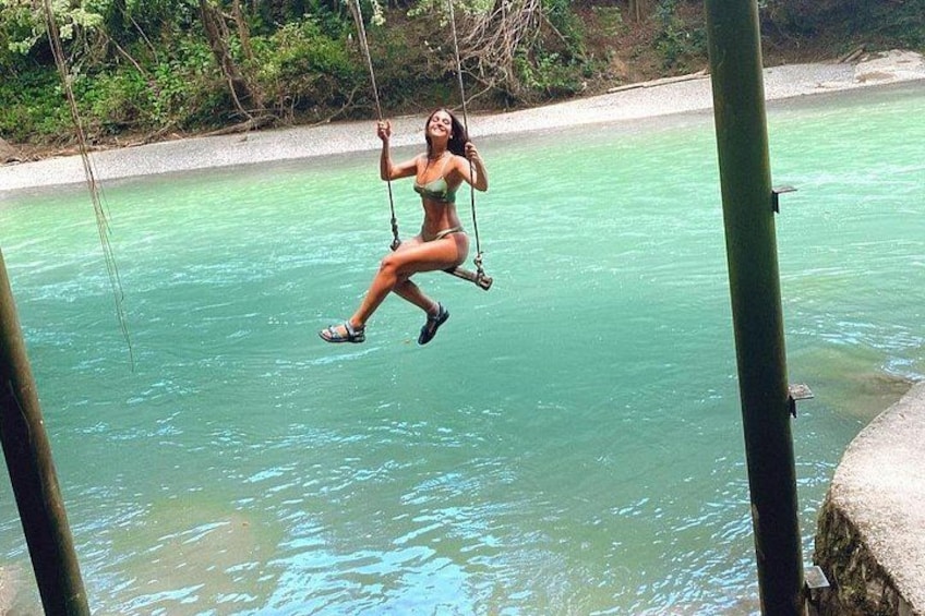 A person swinging over turquoise water. 1